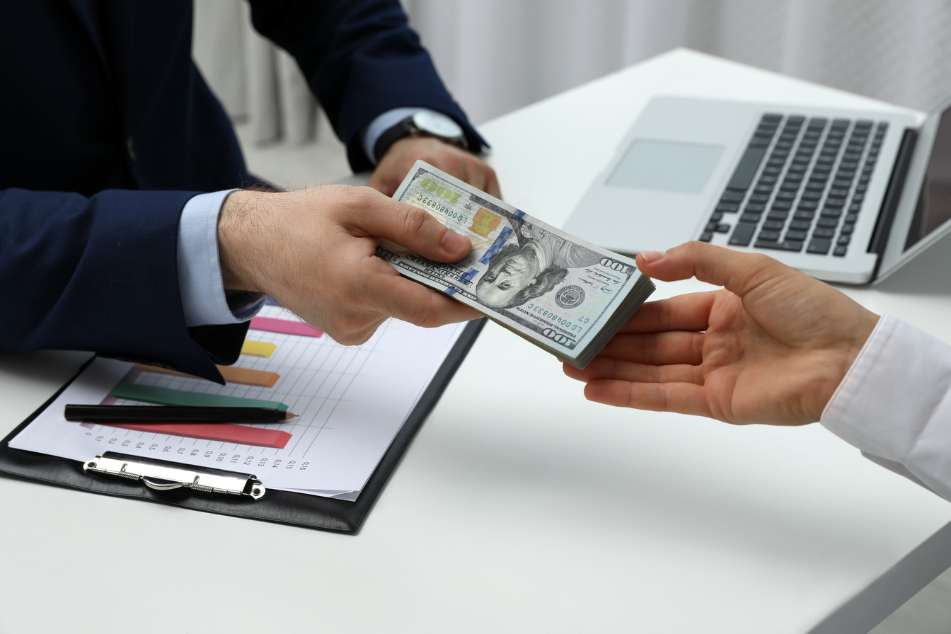 Cashier Giving Money to Businesswoman at Desk in Bank, Closeup